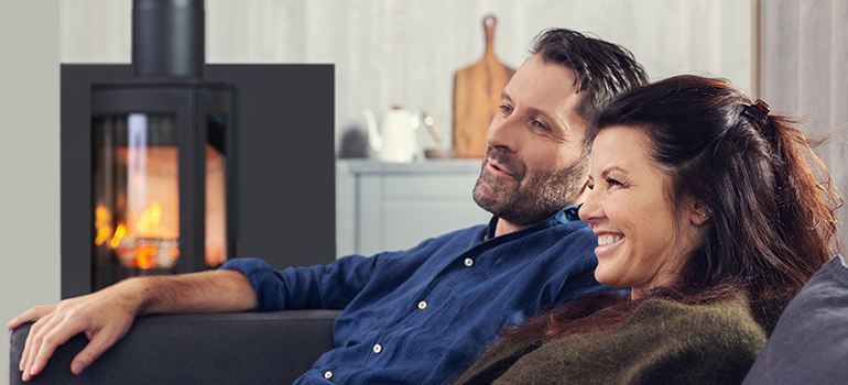 Man and woman sitting in front of the wood stove Jøtul F 373 Advance in the living room 